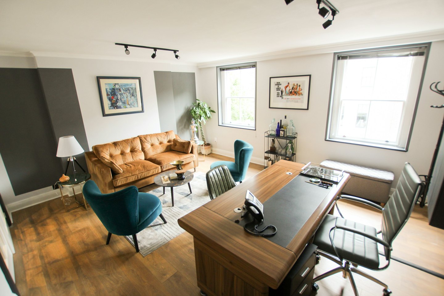 Modernes Büro mit Sofa, Sesseln und Schreibtisch.